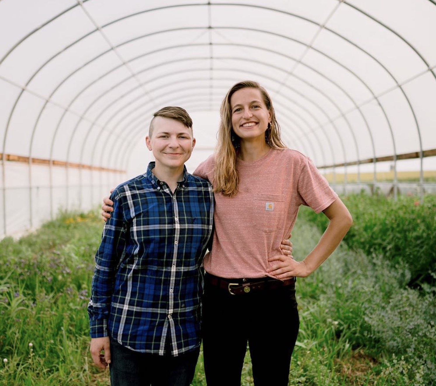 Two farmers standing in their high tunnel 