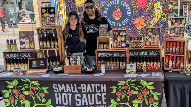 Iowa Pepper co couple standing behind at their hot pepper booth at the farmers market
