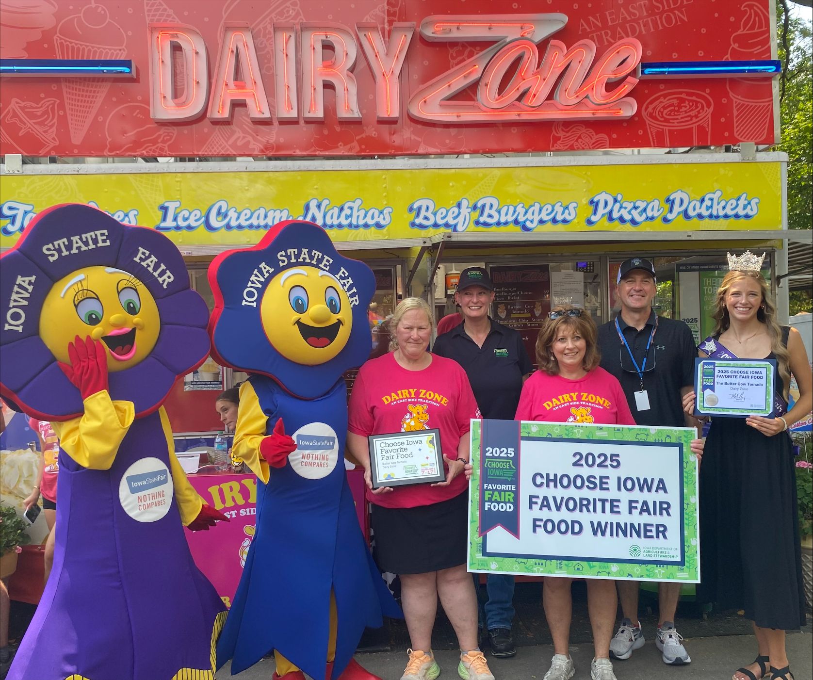 Iowa Secretary of Agriculture Mike Naig (Back Center) is joined by Choose Iowa Director Beth Romer (Back Left), Iowa State Fair Queen Riah Schrage (Back Right), and Fairfield and Rosetta, mascots for the Iowa State Fair, as they present representatives of Dairy Zone with the award for winning the second annual Choose Iowa Favorite Fair Food contest at the 2025 Iowa State Fair. Dairy Zone's The Butter Cow Tornado, featuring Iowa dairy, was chosen by popular vote of fairgoers. Choose Iowa is the state's signature brand for Iowa grown, made, and raised food, beverages, and ag products. It is a program administered by the Iowa Department of Agriculture and Land Stewardship under the leadership of Secretary Naig.