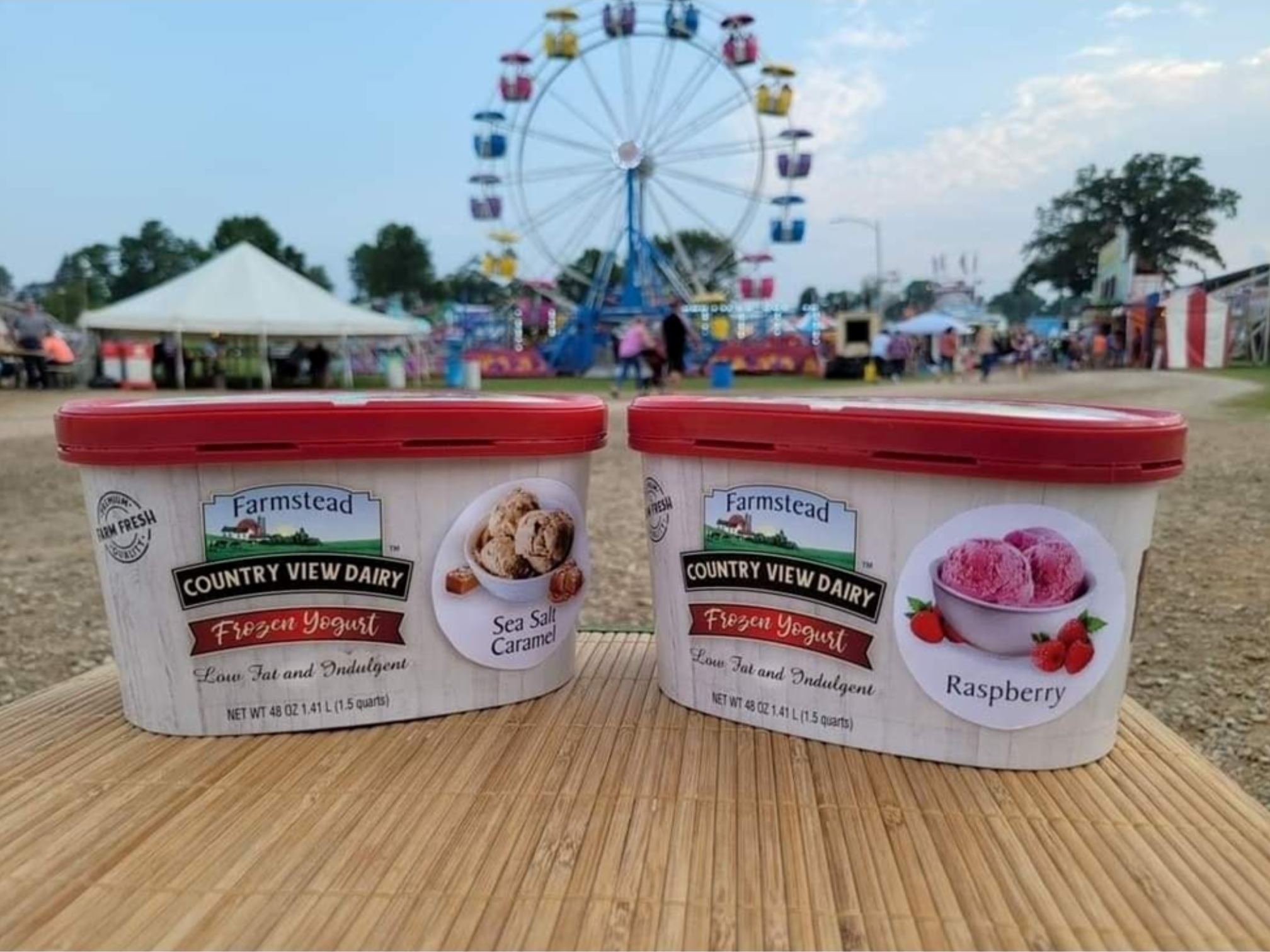 Two containers of ice cream sit displayed in front of a ferris wheel.