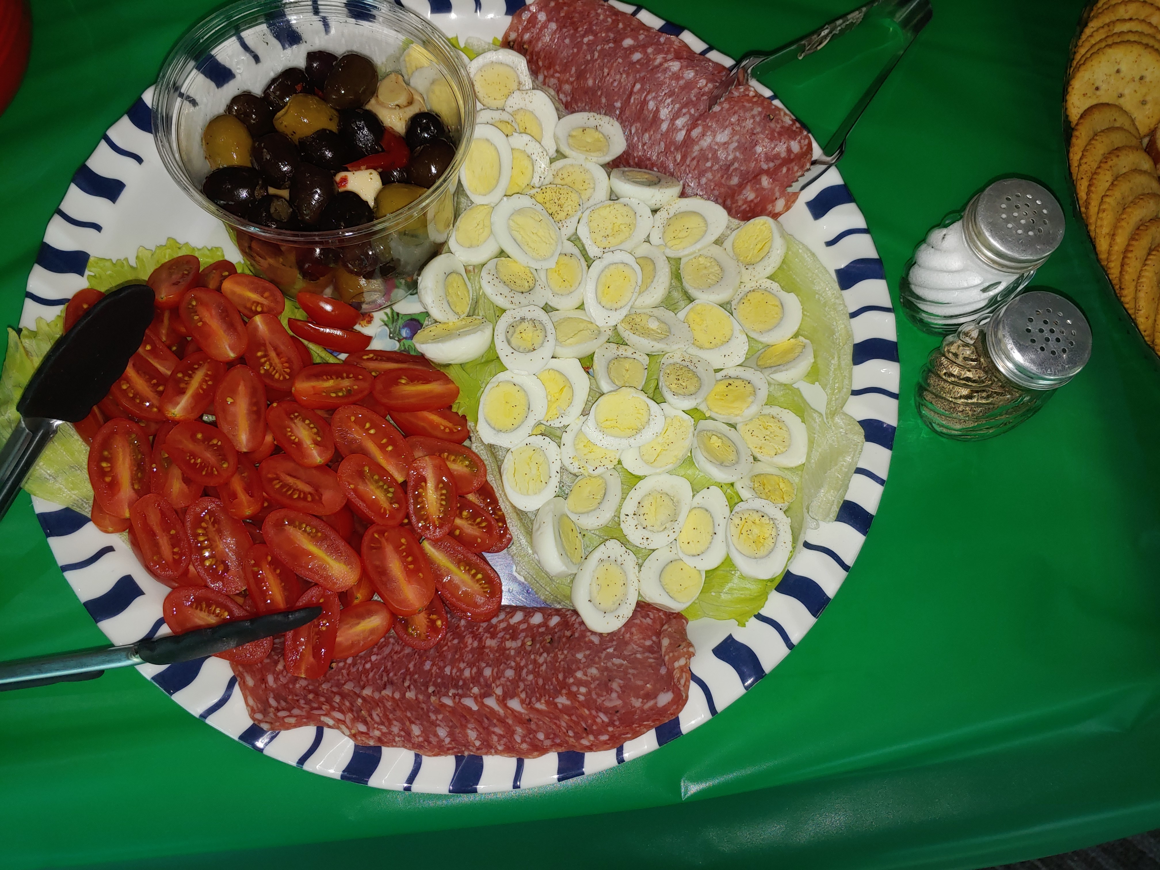 A plate features quail eggs, tomatoes, salami, and olives ready to eat.