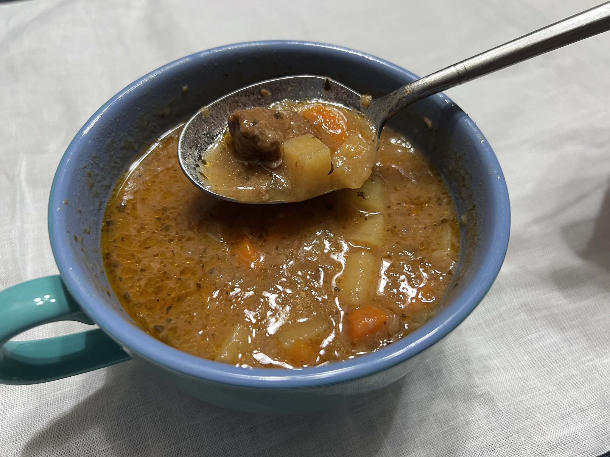 A blue bowl of beef stew sits ready to be eaten