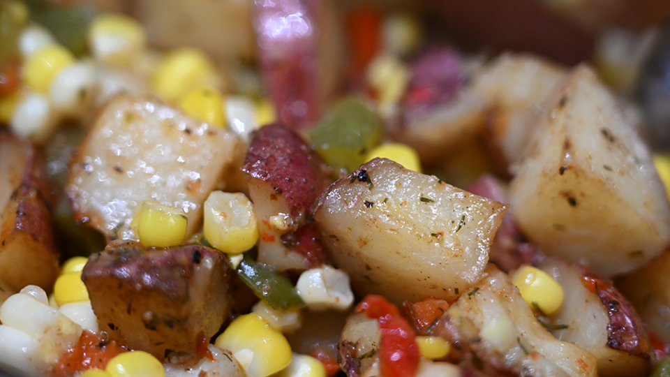 A mixture of sweet corn, peppers, and potatoes is ready for eating.