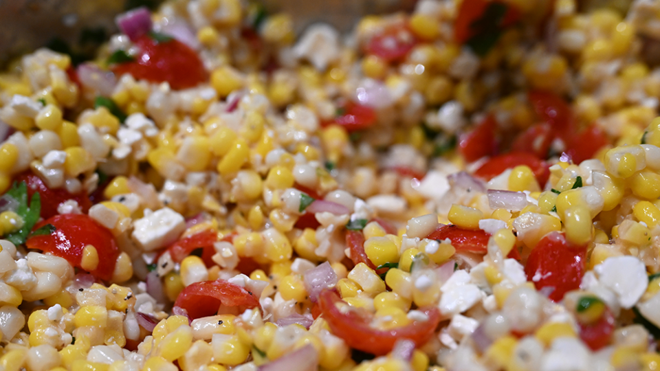 A corn salad with tomatoes and feta cheese.