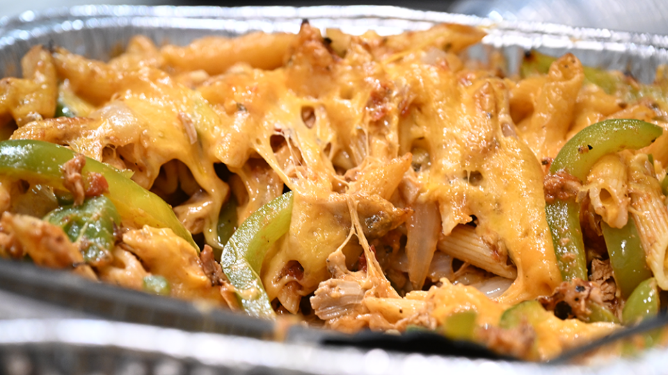 Penne pasta and green bell peppers are mixed with chicken and cheese.