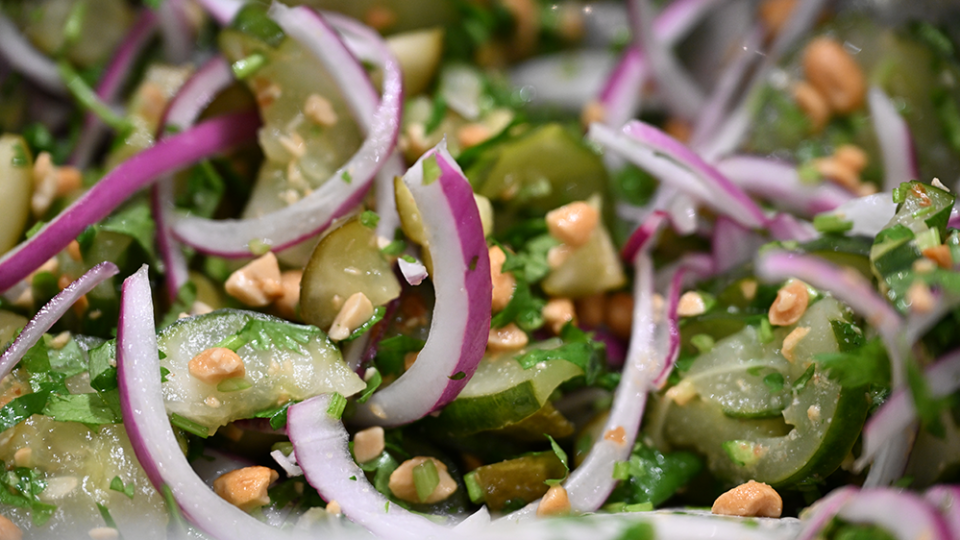 Pickles are mixed with slices for onion and peanut pieces in a bowl.