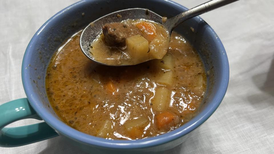 A blue bowl of beef stew sits ready to be eaten
