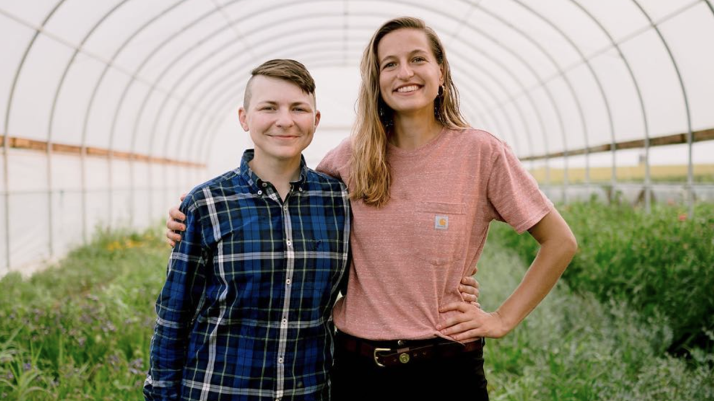 Two farmers standing in their high tunnel