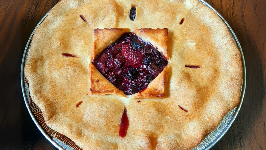 A scrumptious Mixed Berry Pie sitting on a wooden table.
