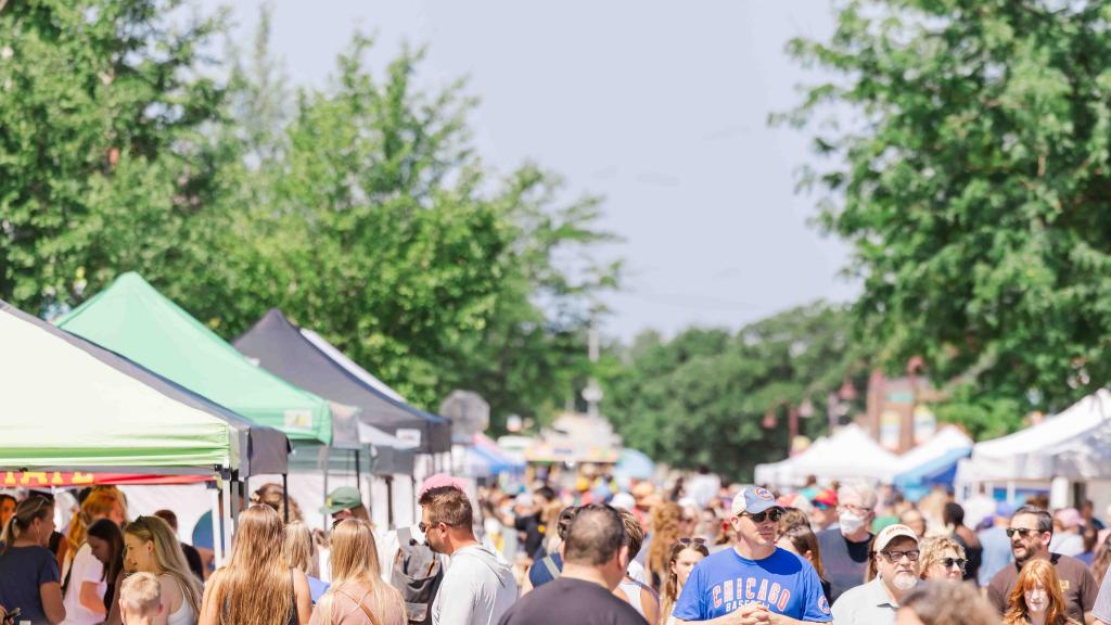 people walking the street lined with vendors at the Ames Main Street Farmers Market
