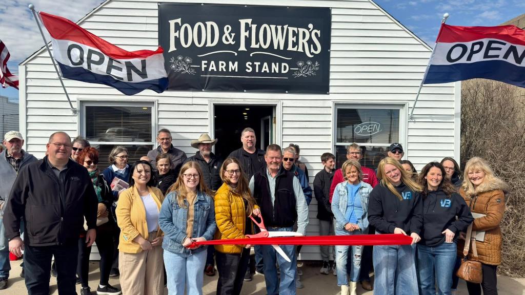 Group of people cutting a ribbon at the grand opening for Food and Flowers Farm Stand in Charter Oak, Iowa.