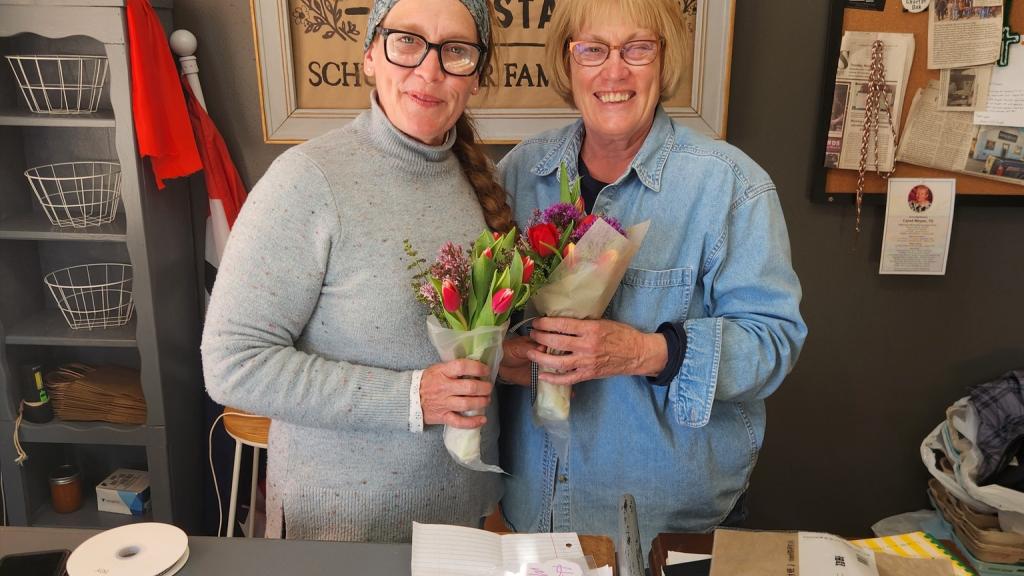 two women holding wrapped bouquets of fresh flowers in Food and Flowers Farm Stand near Charter Oak, Iowa