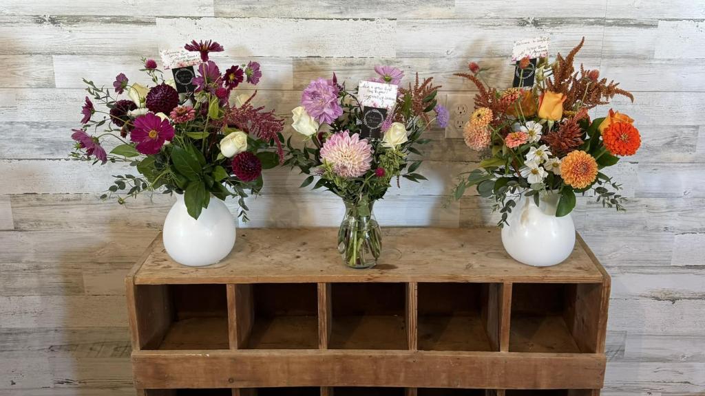 Locally grown flower arrangements on display on a rustic shelf.
