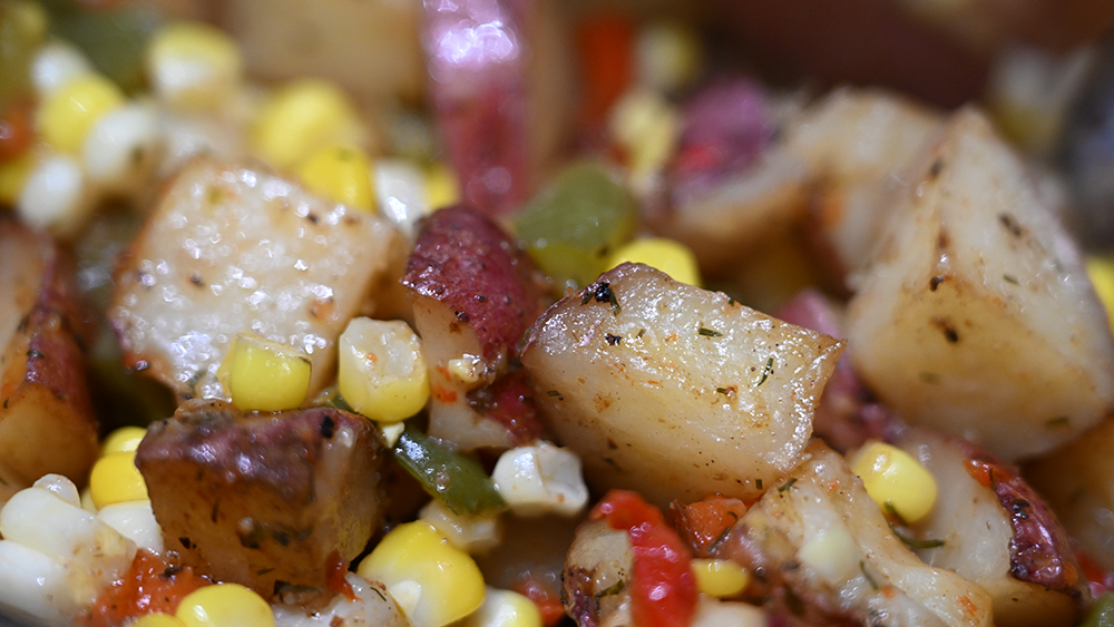 A mixture of sweet corn, peppers, and potatoes is ready for eating.